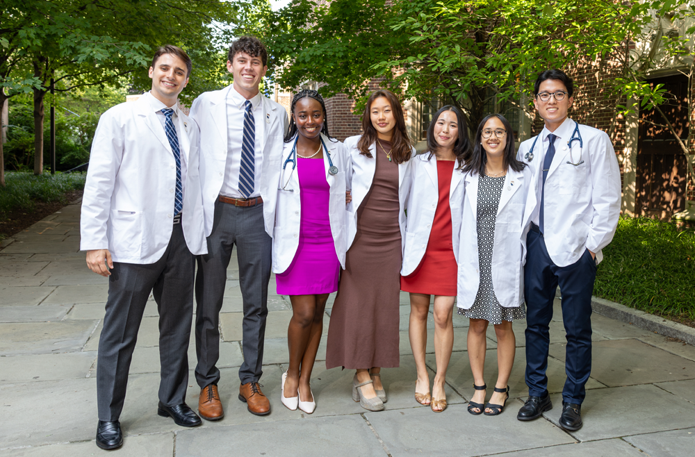 A group of students posing outside in their white coats